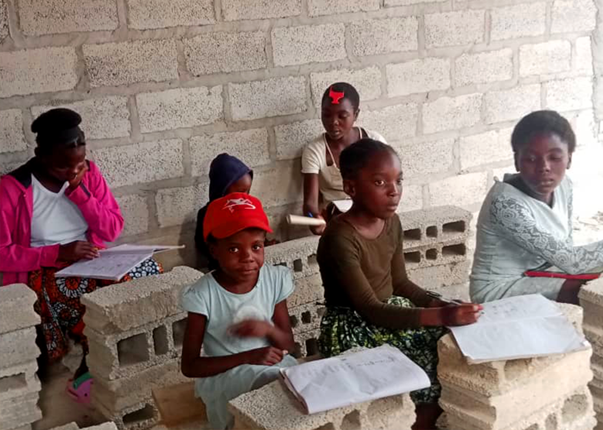 A group of children studying with their notebooks in the temporary classroom of Twafweni.