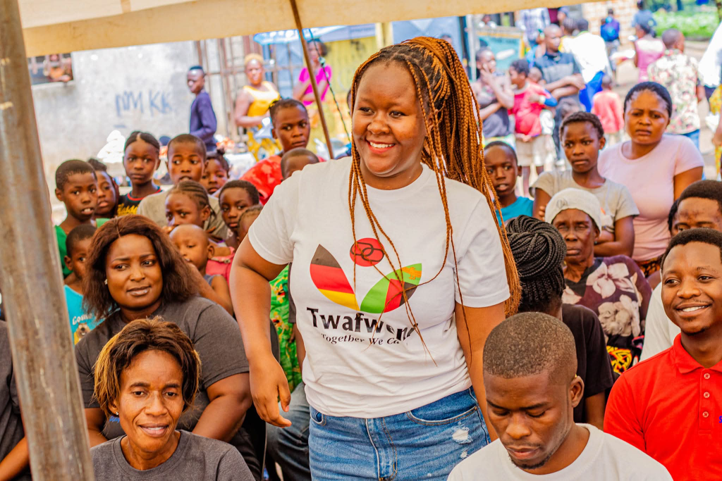 A group of smiling people with a woman wearing a Twafweni shirt in the middle